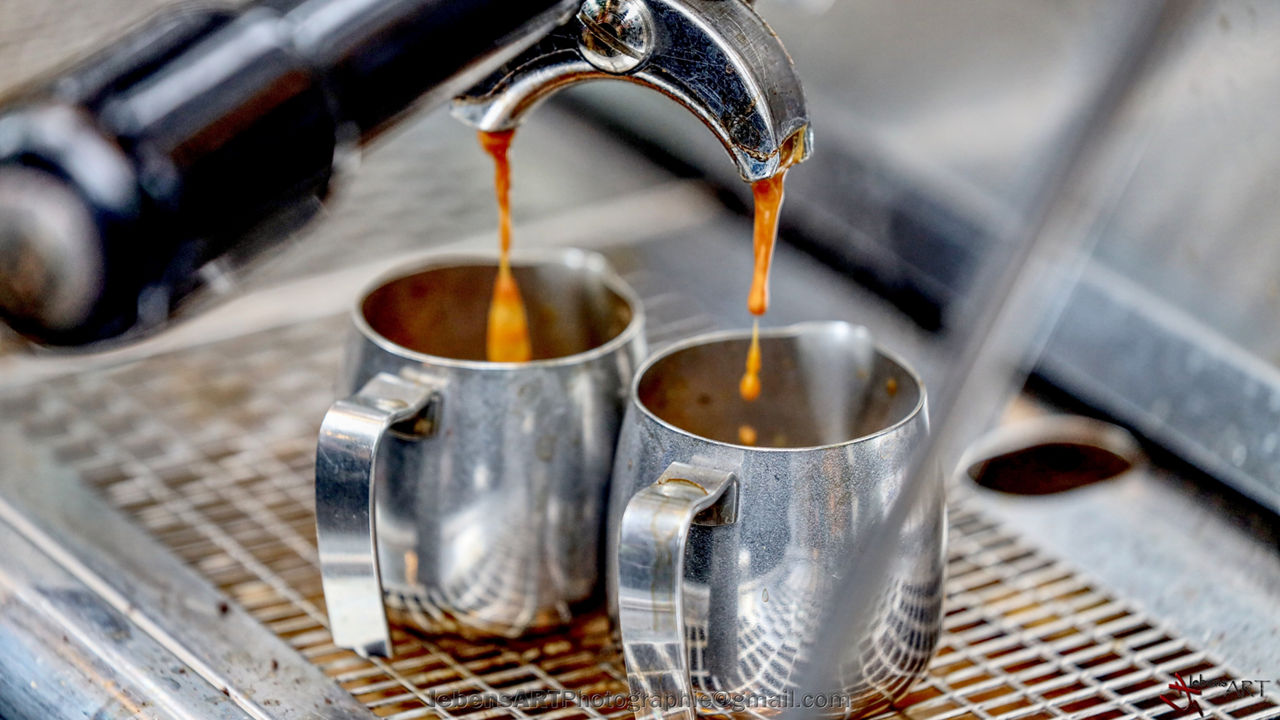 Aus der Maschine läuft gerade frischer Kaffee und wird in den Kaffeebechern eingefüllt.